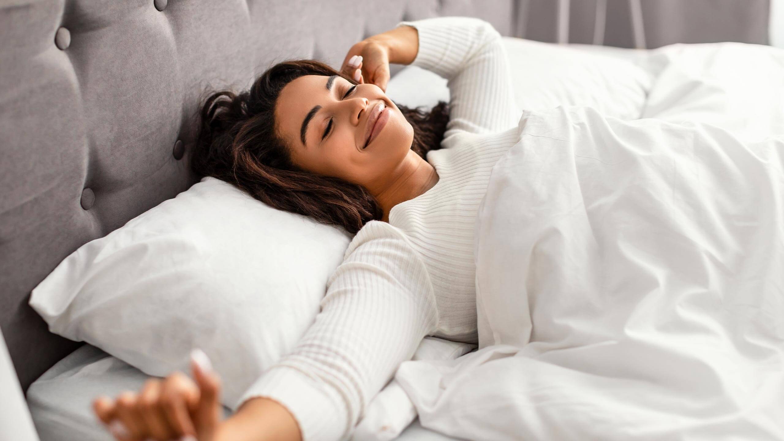 Woman waking rested in a bright bedroom