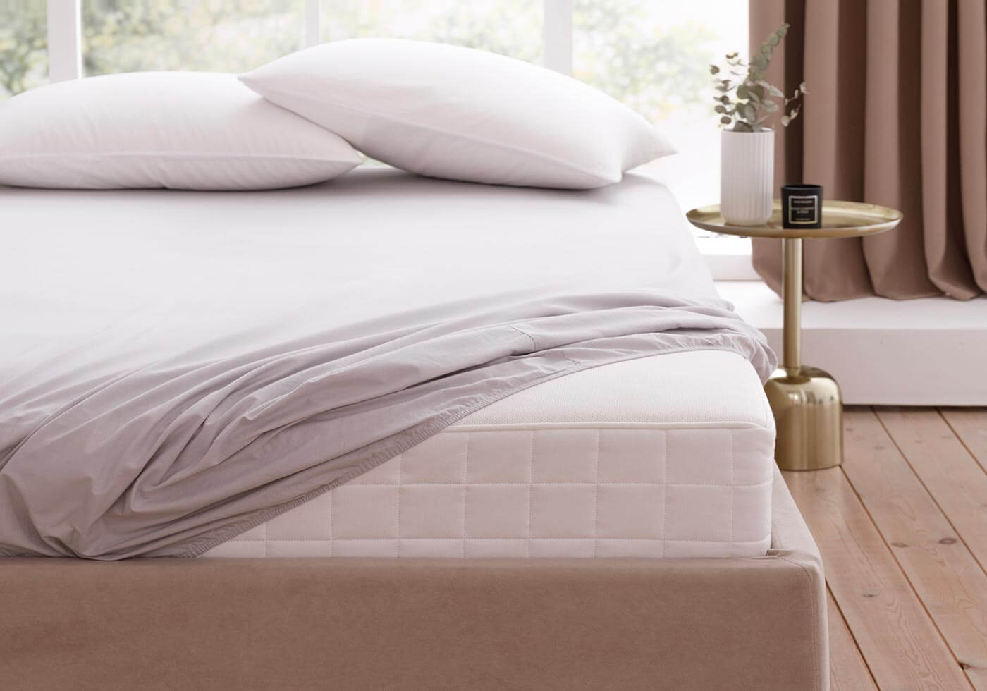 Corner of a custom mattress dressed with crisp white sheets